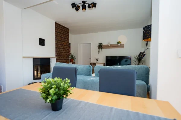 Wohnzimmer der Ferienwohnung Augustus mit Esstisch, grauen Stühlen und Kamin